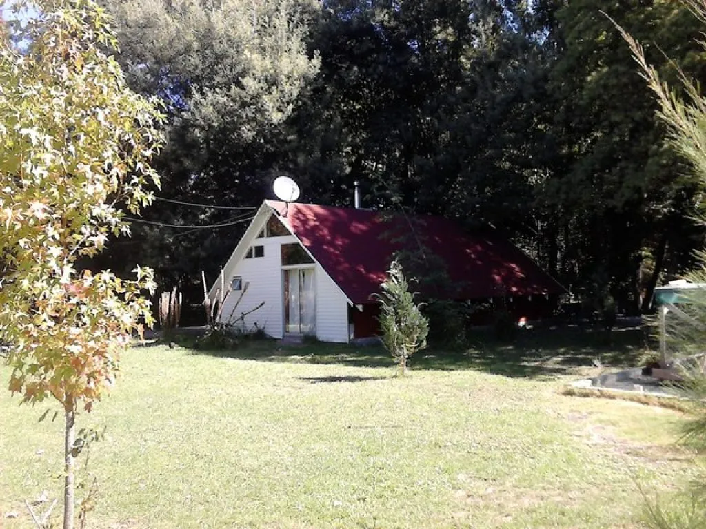 Vista exterior del complejo Los Manantiales con piscina, jardines y cabañas al fondo